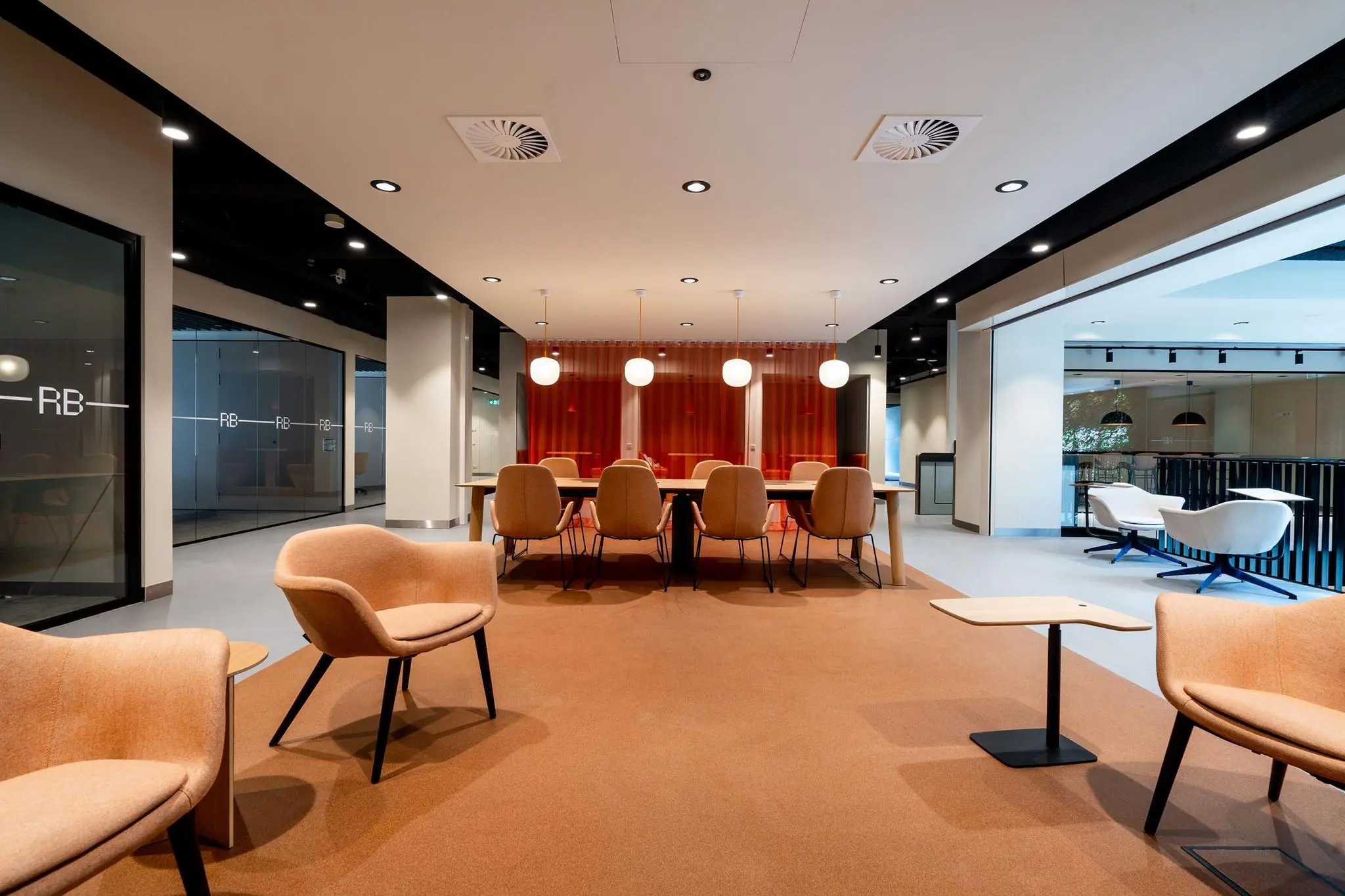 Moderne kantoorruimte aan de Aert van Nesstraat met vergadertafel, sfeervolle verlichting en zithoeken in warme tinten.